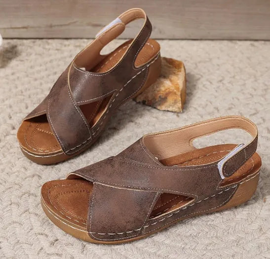 Women's brown platform Roman sandals with skirted ankle strap and Velcro fastening on a white background.