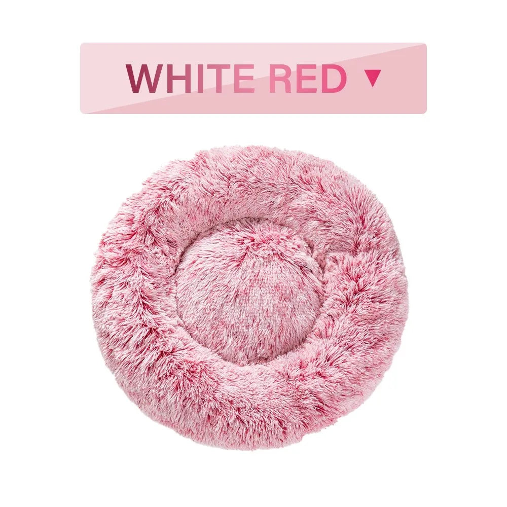 Fluffy donut-shaped dog bed in long plush material, shown in a light grey colour with a raised edge.
