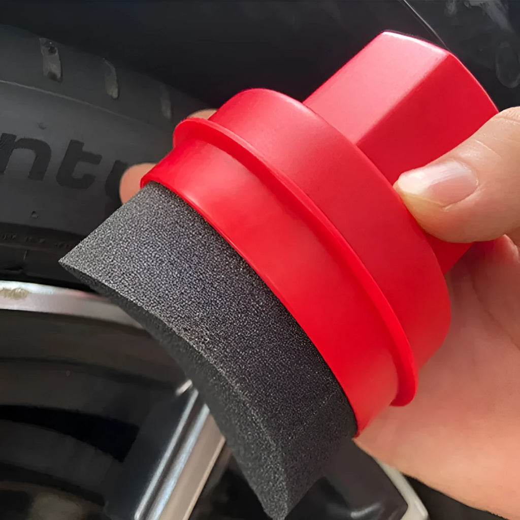 Hand-held black and red car tyre polishing sponge brushes with lids on a garage workbench.