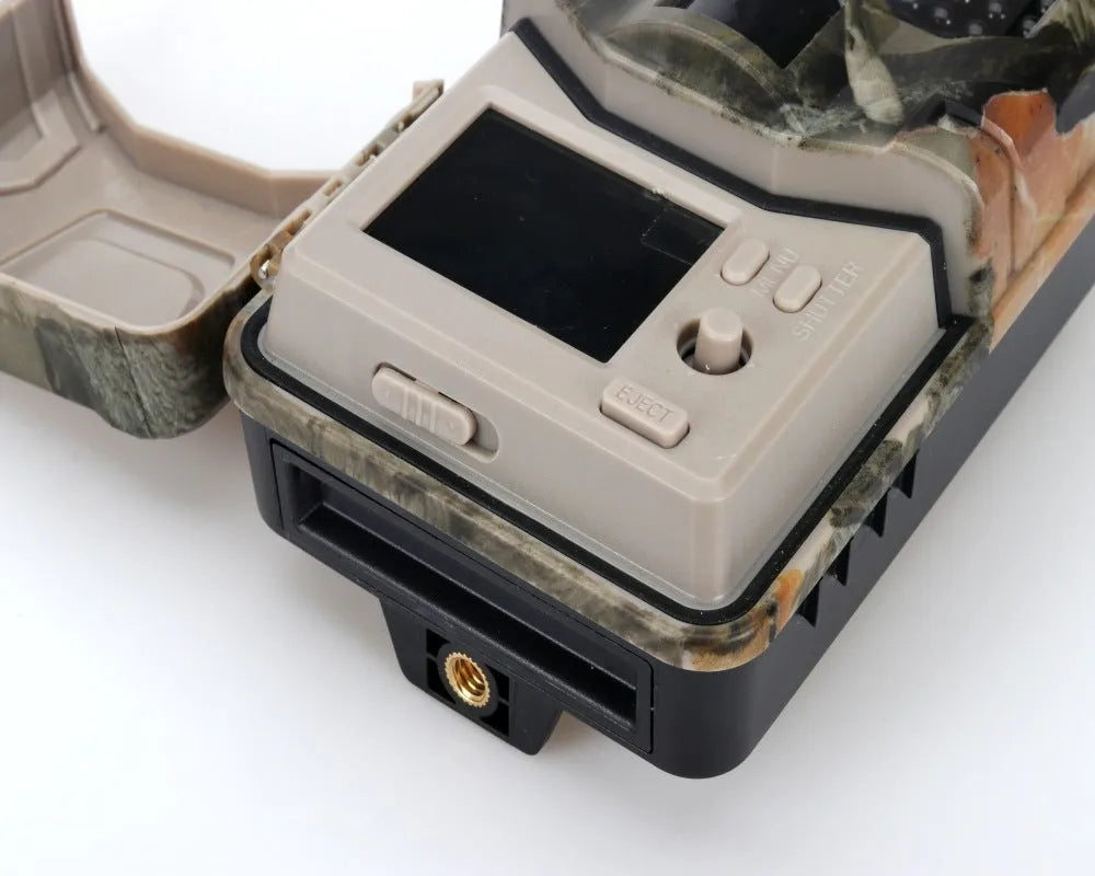 Camouflaged outdoor trail camera showing lens, infrared LEDs, and compact body for wildlife and security monitoring.