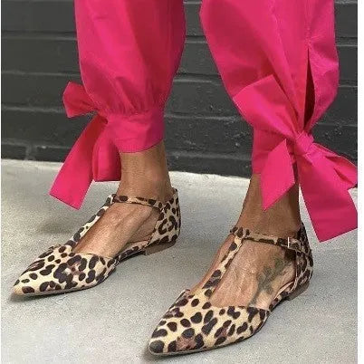 Leopard print women's pumps with a low chunky heel, pointed toe, and cross ankle straps.