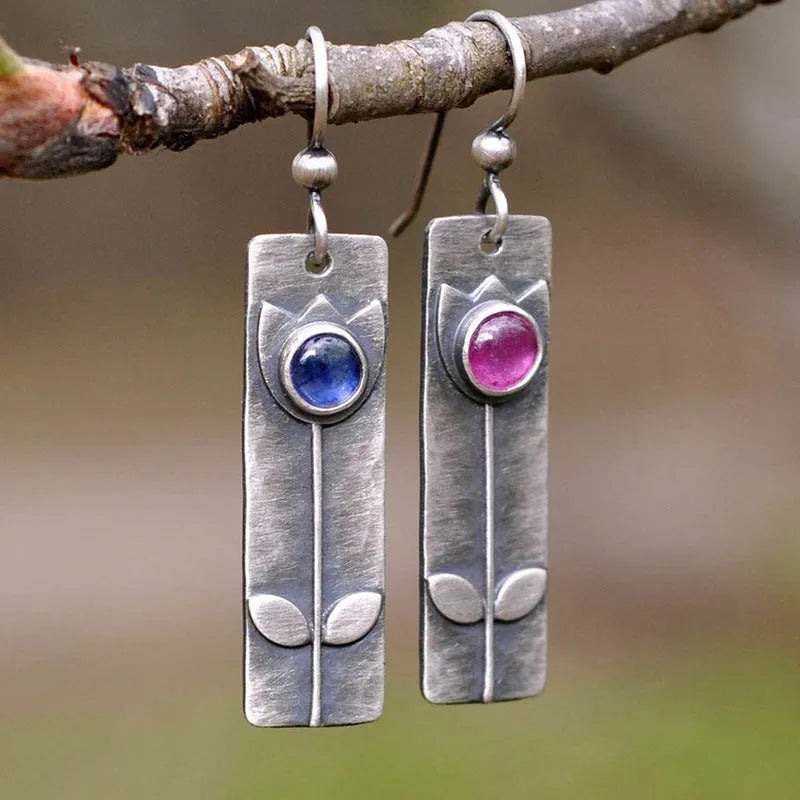 A pair of red sapphire earrings with an antique finish and geometric elliptical shape.