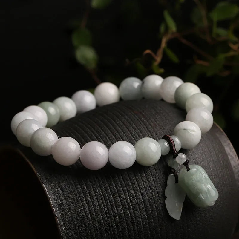 Natural green jade bracelet with a geometric pendant charm on a wrist.