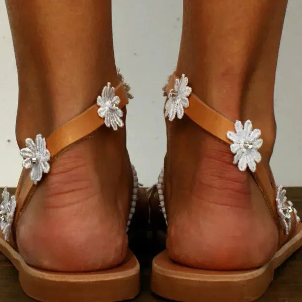 Brown women's flat sandals with floral pattern and herringbone toe on a rubber sole.