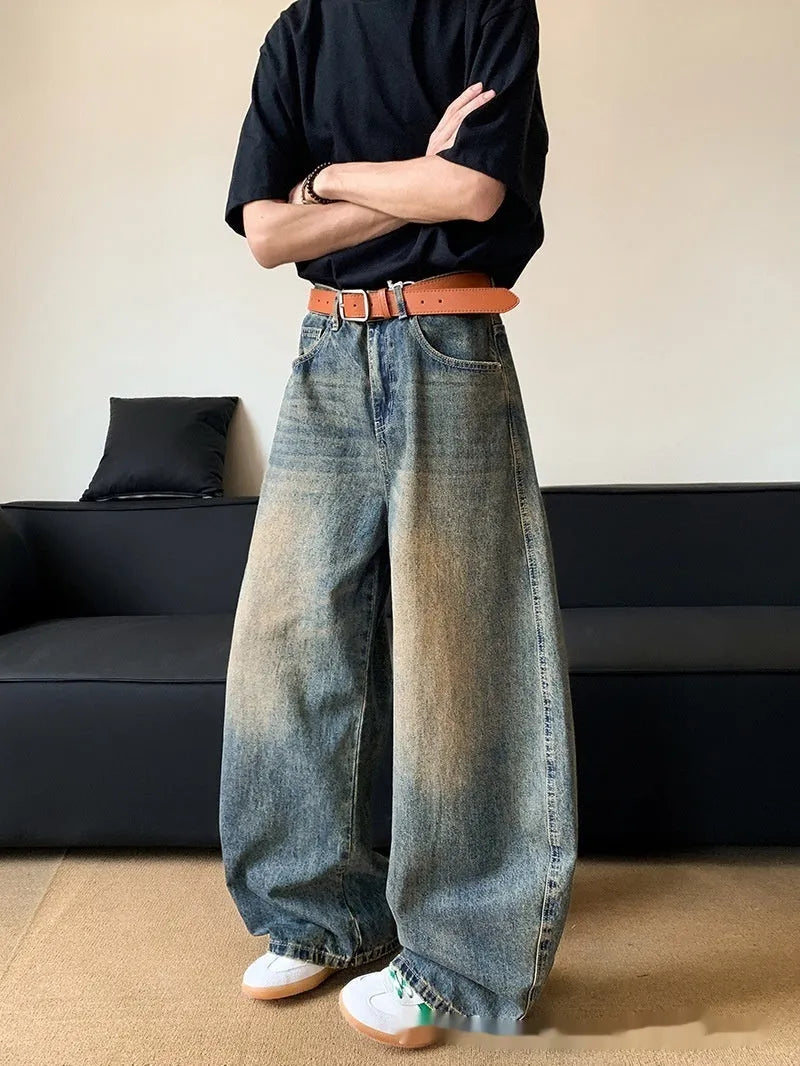 Man wearing retro blue distressed denim jeans with a slim-fit wide-leg cut.