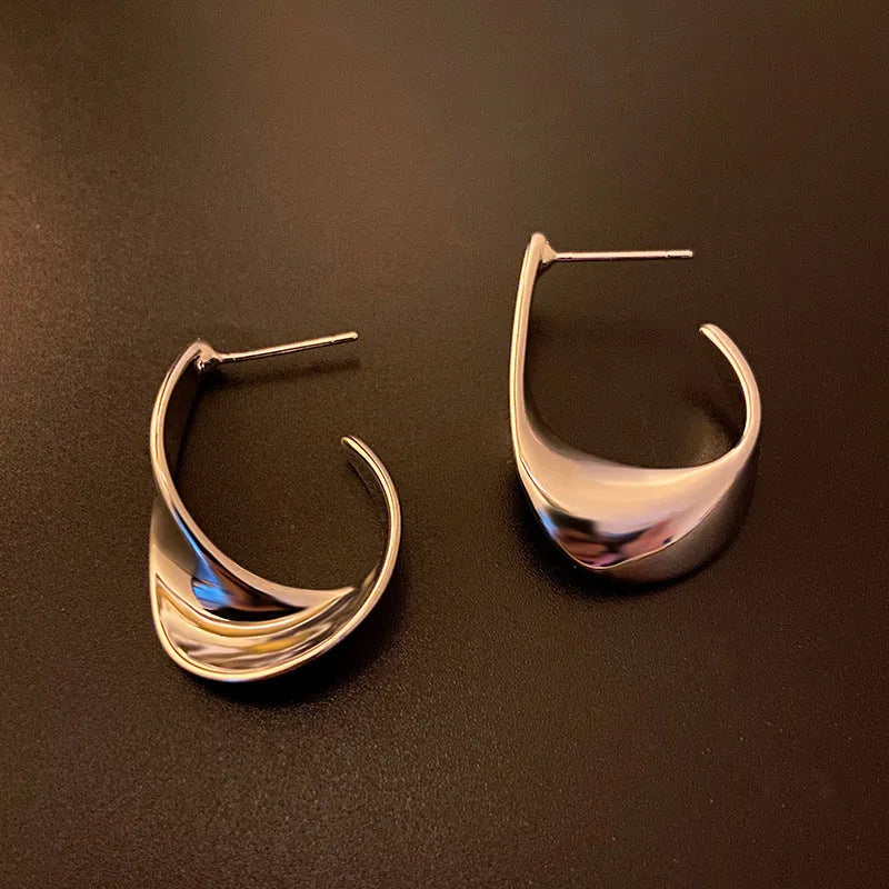 A pair of round, twisted geometric metal earrings with a gold electroplated finish.