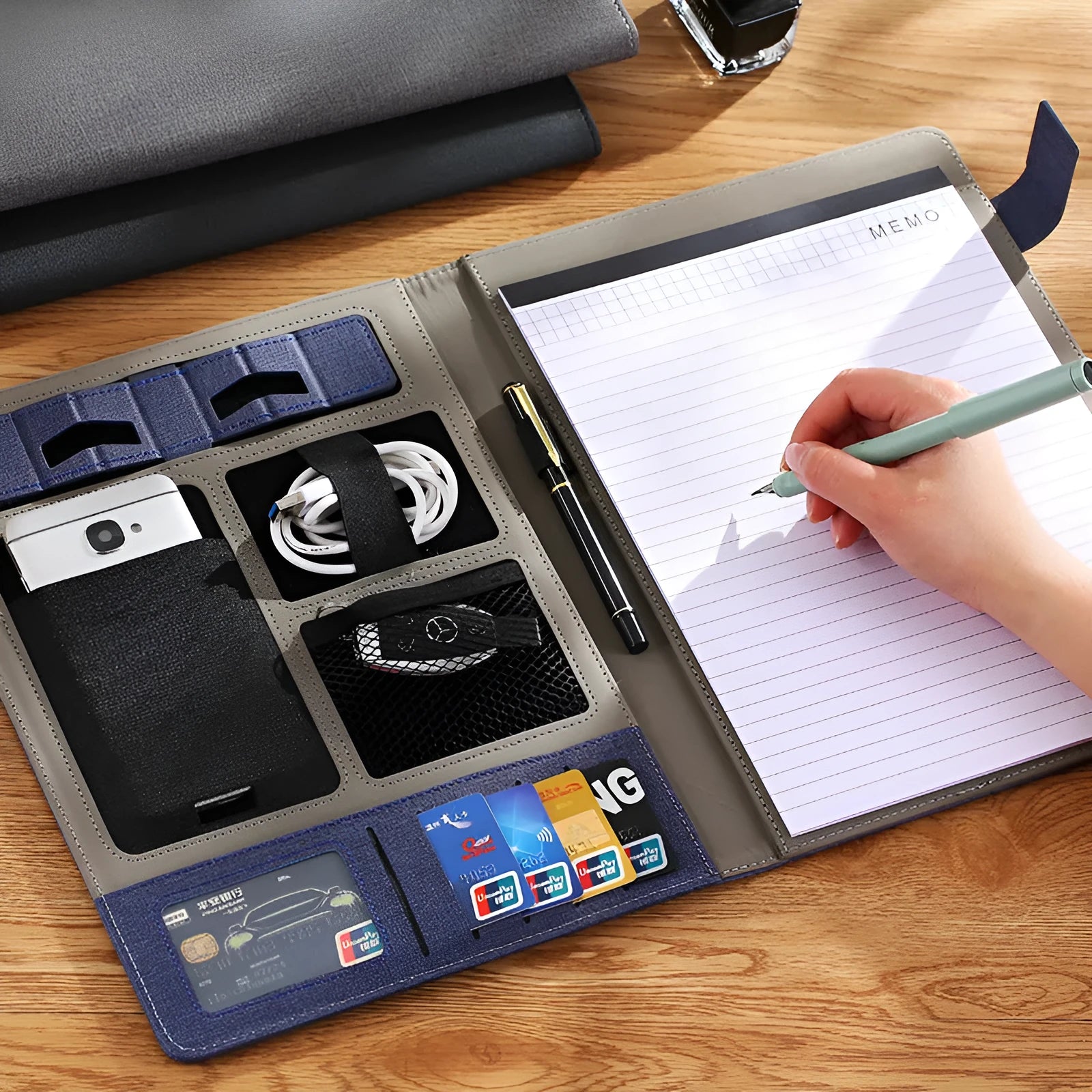 Black leather A4 business folder with a pen and notepad on a desk