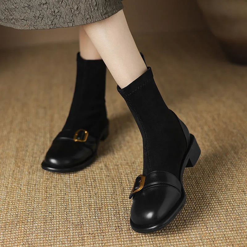 Black women's low heel Martin boot with belt buckle stitching and lace-up front on a rubber sole.