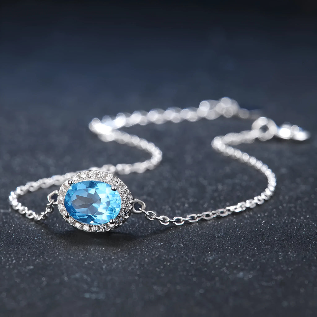Four-piece 925 Sterling Silver geometric jewellery set with blue topaz gems, showing earrings, ring, pendant, and necklace.