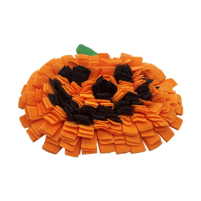 Orange pumpkin-shaped pet training mat on floor with dog treats scattered across polar fleece surface