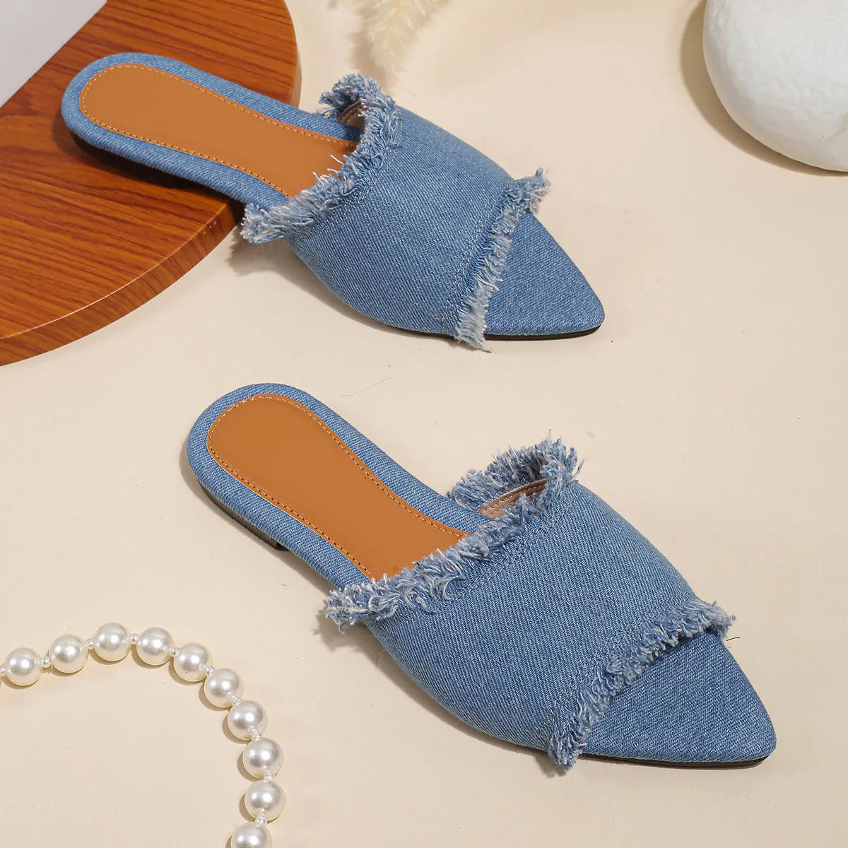 Women's flat denim slippers with tassel detail in apricot colour on a white background