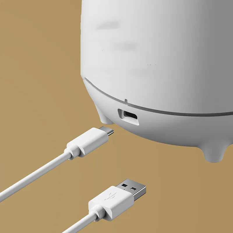 White volcano-shaped ultrasonic humidifier with USB cable on a wooden table.