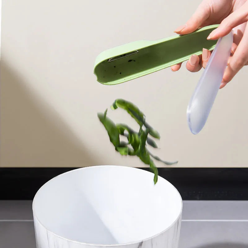 Dark green kitchen peeler with a stainless steel blade extended from its storage tube, showing the non-slip handle.