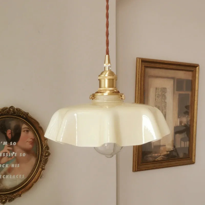 Medieval-style brass flower bud chandelier with a cream glass shade hanging from an adjustable cord.