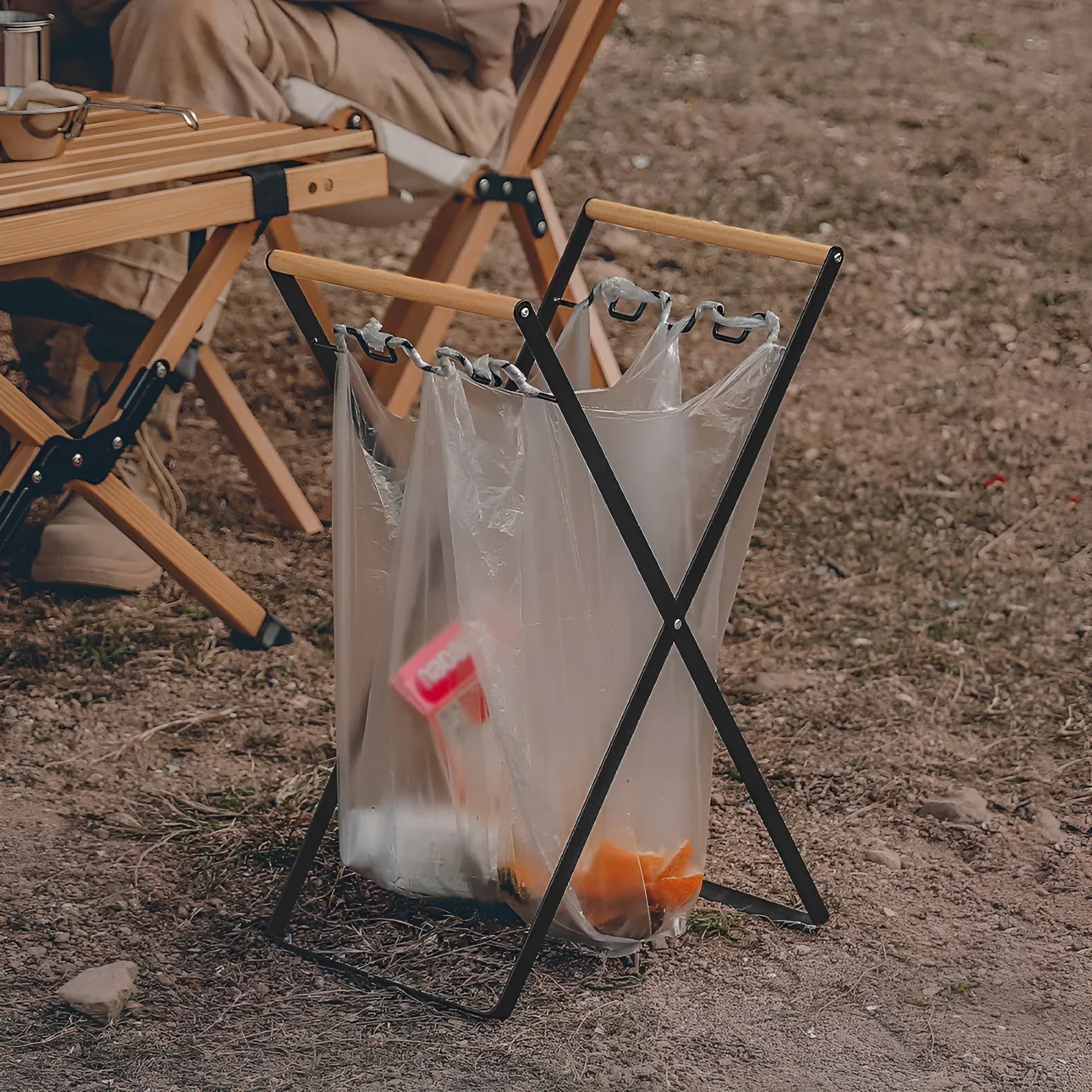 Black folding iron trash rack with wooden handles holding a bin bag outdoors