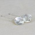 Silver-toned round earrings with bird and leaf elements, glossy finish, approximately 2-3cm diameter