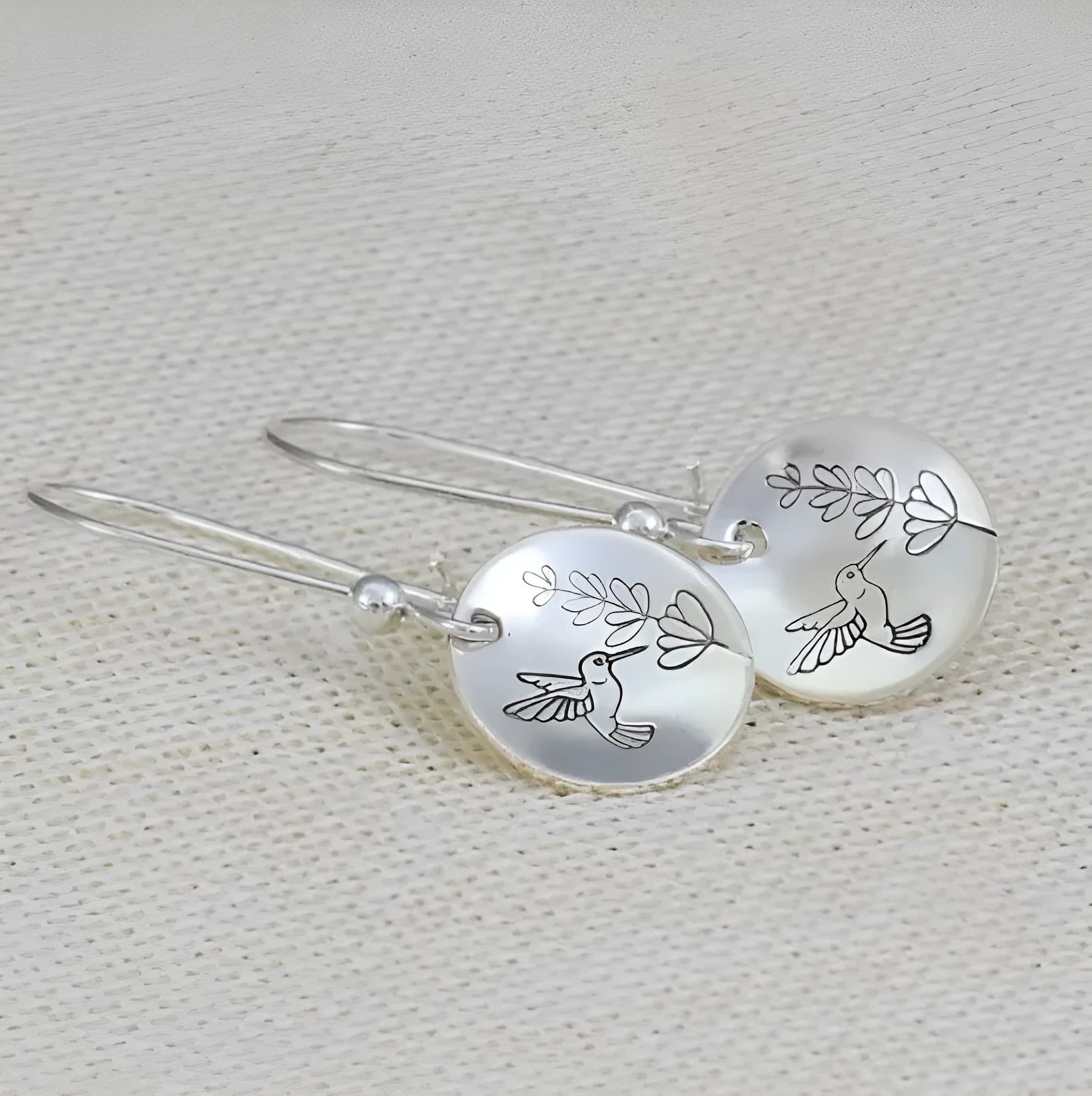 Silver-toned round earrings with bird and leaf elements, glossy finish, approximately 2-3cm diameter