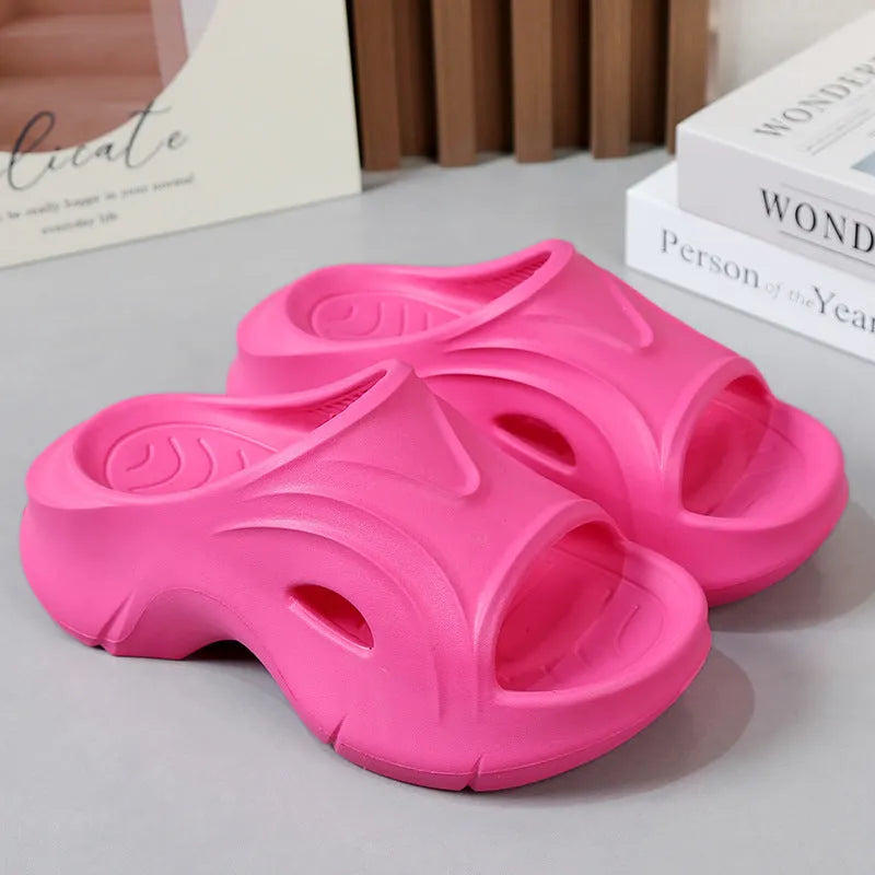 Women's white EVA slippers with a thick sole and round toe on a sandy beach.