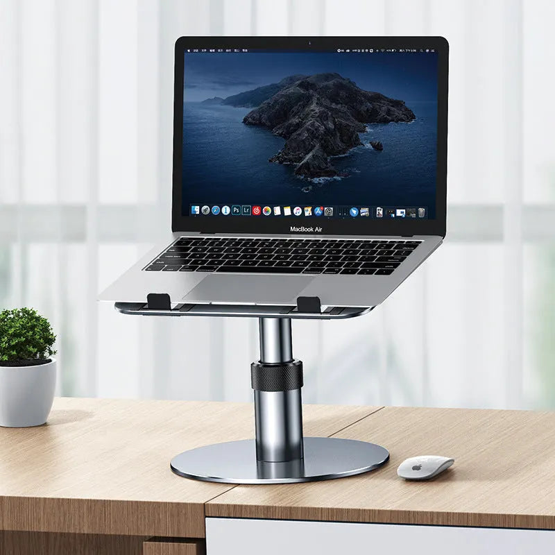 Silver adjustable aluminum laptop stand with non-slip pads on a desk next to a laptop.