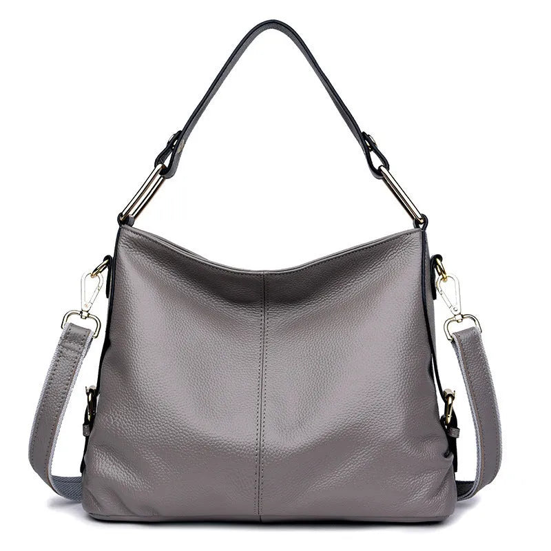 Genuine leather vertical square crossbody bag in black showing outer pocket and structured shape.