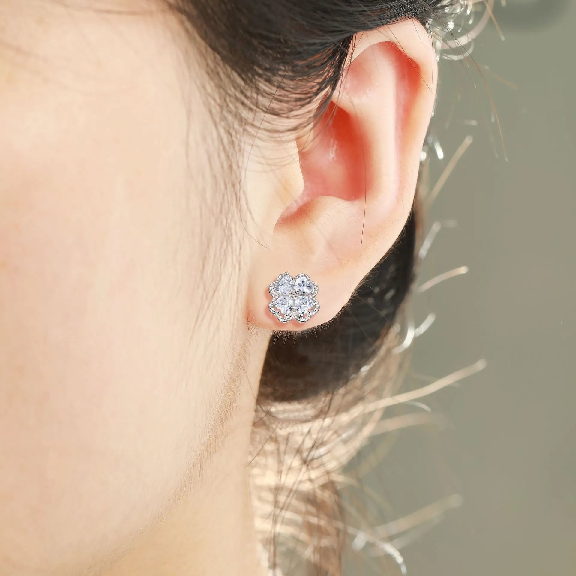Close-up of women's 925 silver earrings with a four-leaf clover and heart design, inlaid with zircon stones in white gold colour.