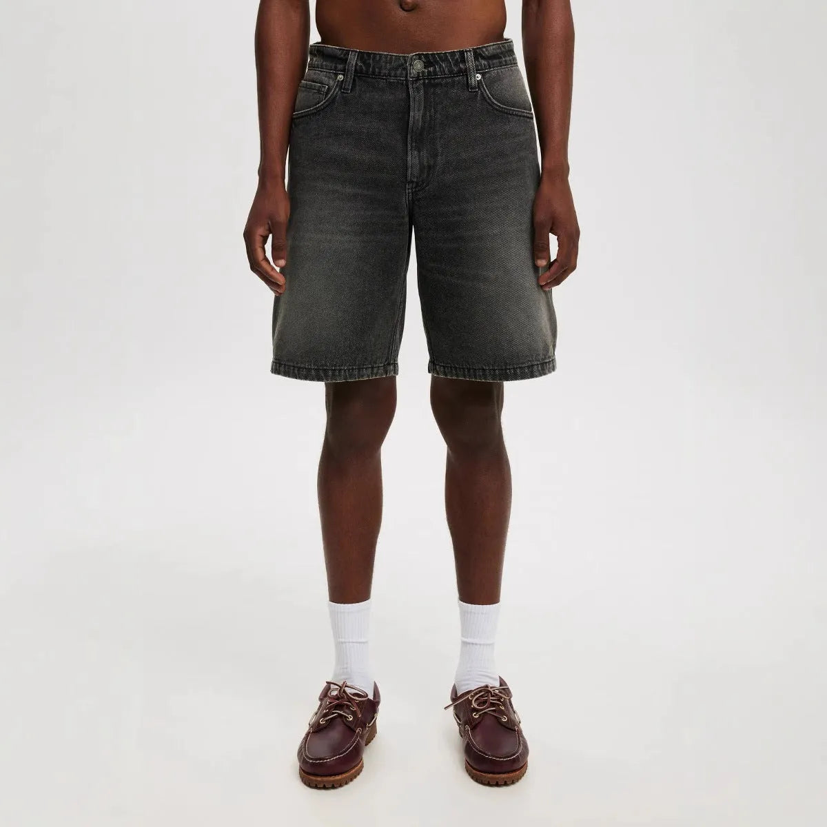 Man wearing loose straight leg jeans in light blue cotton denim, front and side view.