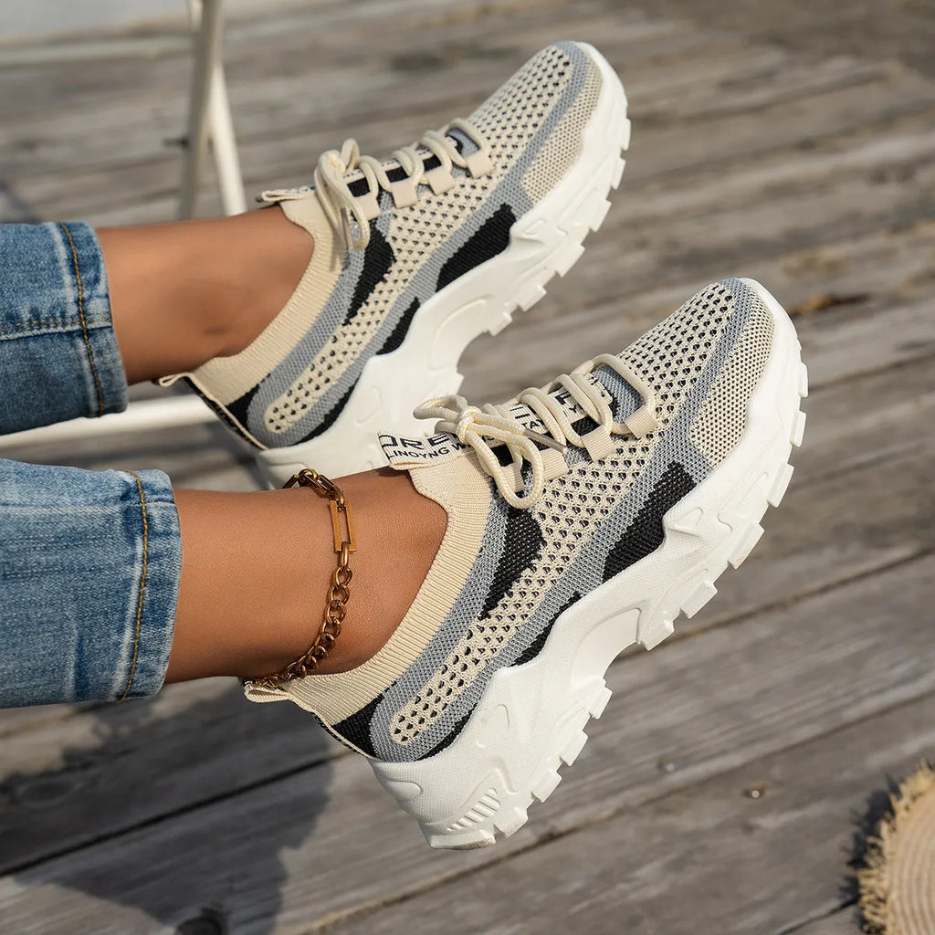 Women's Flyknit mesh lace-up sneakers in a grey colourway on a flat rubber sole.