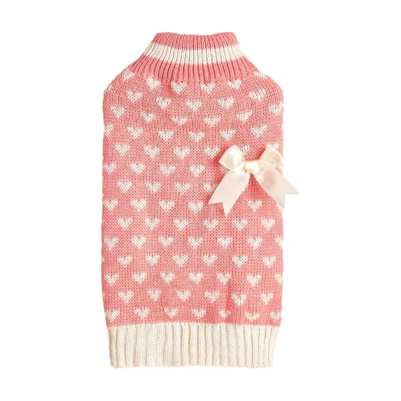Dog wearing acrylic jumper with love heart and bow designs in red and pink colour patterns