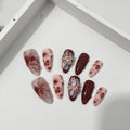 False nails set with three-dimensional hand-painted rose, tulip, shell, bow, and leopard print designs in almond colour
