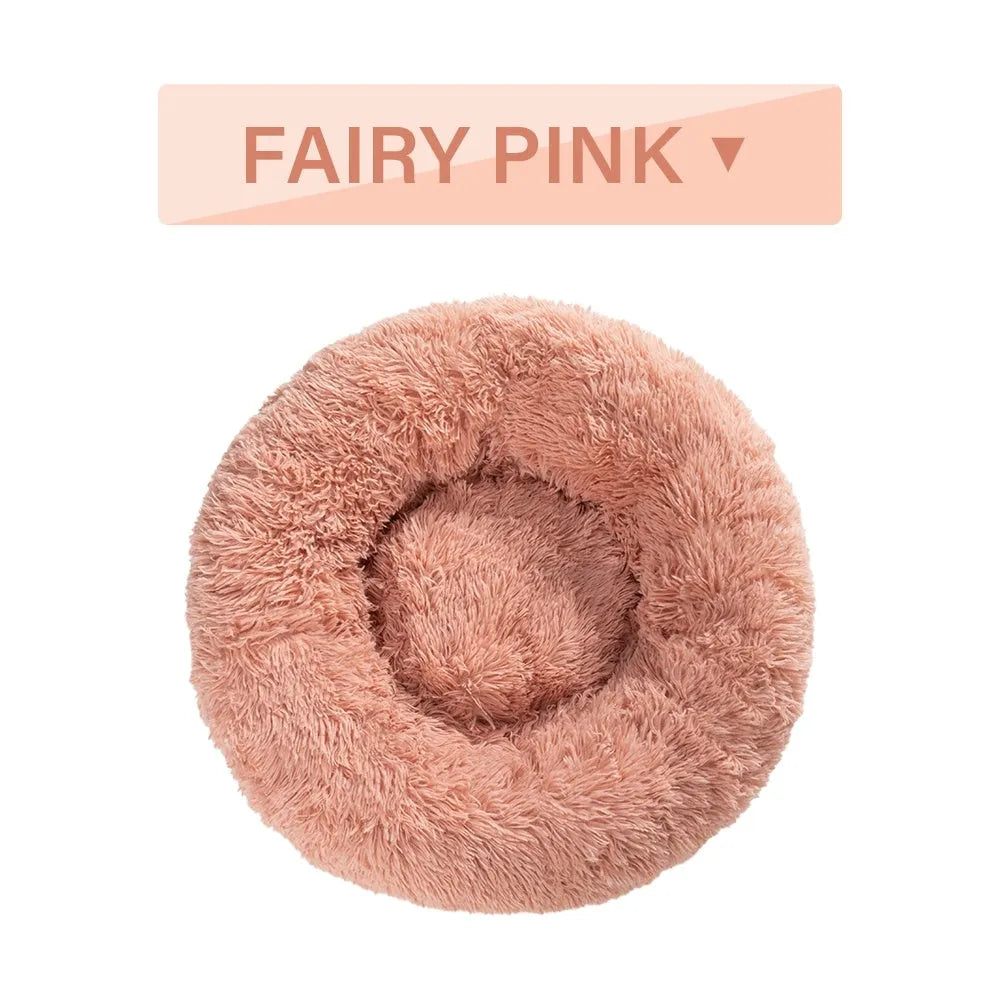 Fluffy donut-shaped dog bed in long plush material, shown in a light grey colour with a raised edge.
