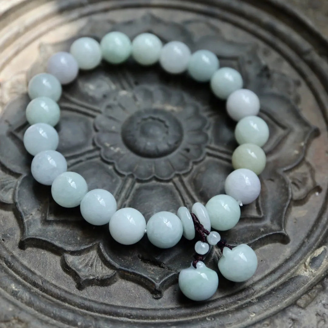 Natural green jade bracelet with a geometric pendant charm on a wrist.