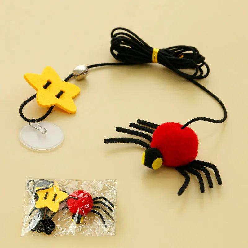 Red door hanging cat toy with elastic rope, feather, bell, and spider attachment on a white door.