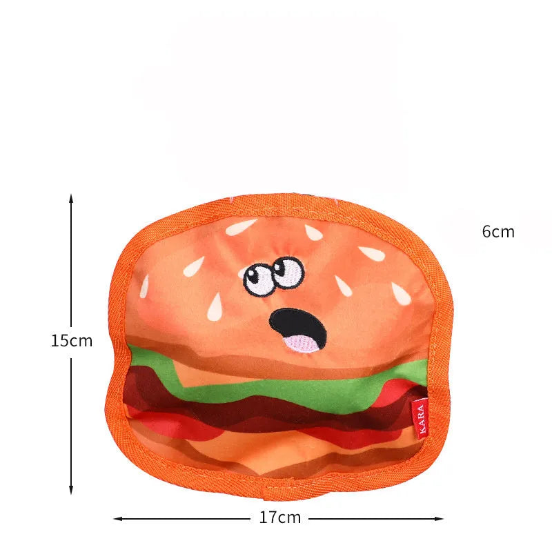 Colourful crinkle and squeaky dog chew toys shaped like a hamburger, fries, a hot dog, and a pizza on a plain background.