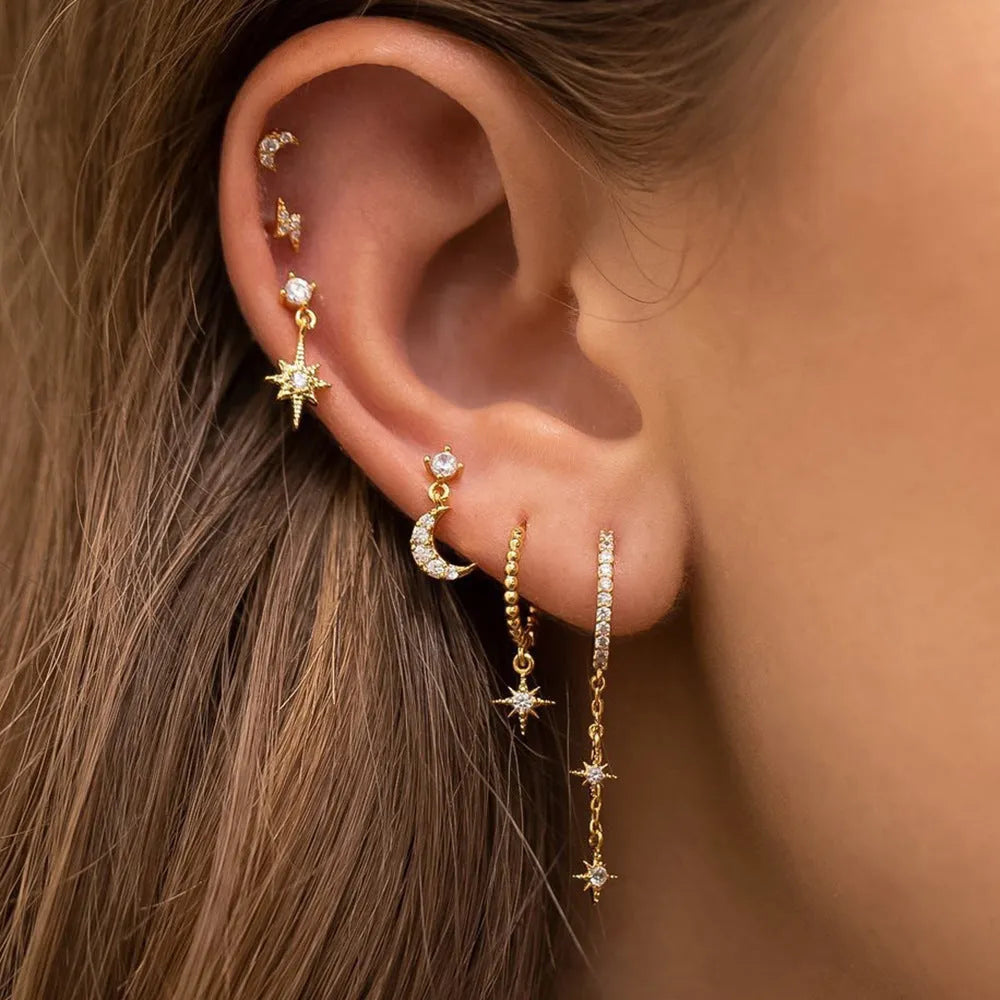 Six pairs of gold chain tassel earrings with zircon studs displayed together