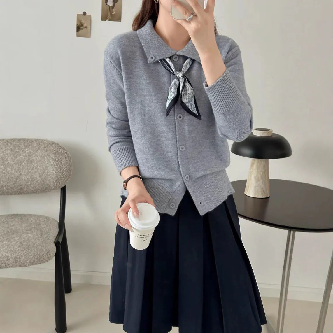 Beige cardigan sweater with a built-in lapel scarf and long sleeves laid flat