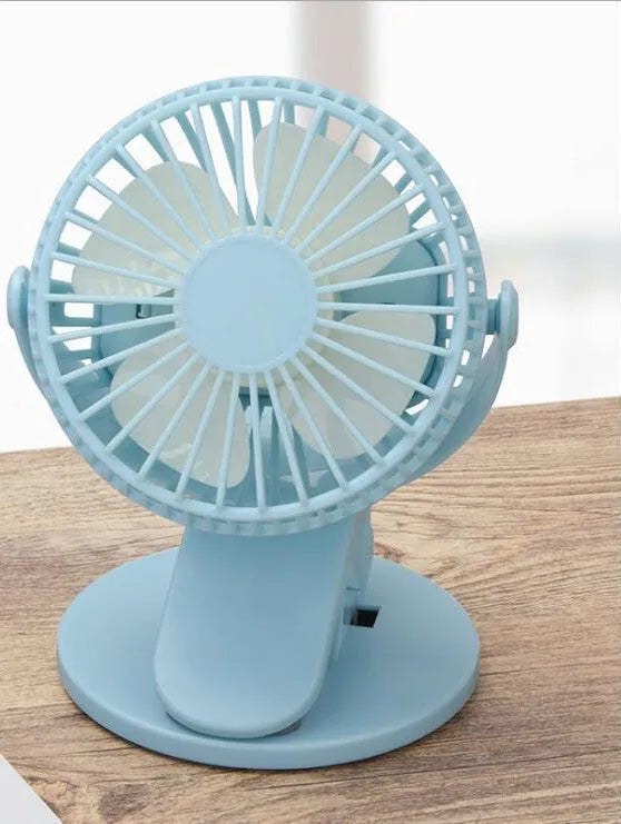 Small white USB rechargeable clip fan attached to a desk edge.