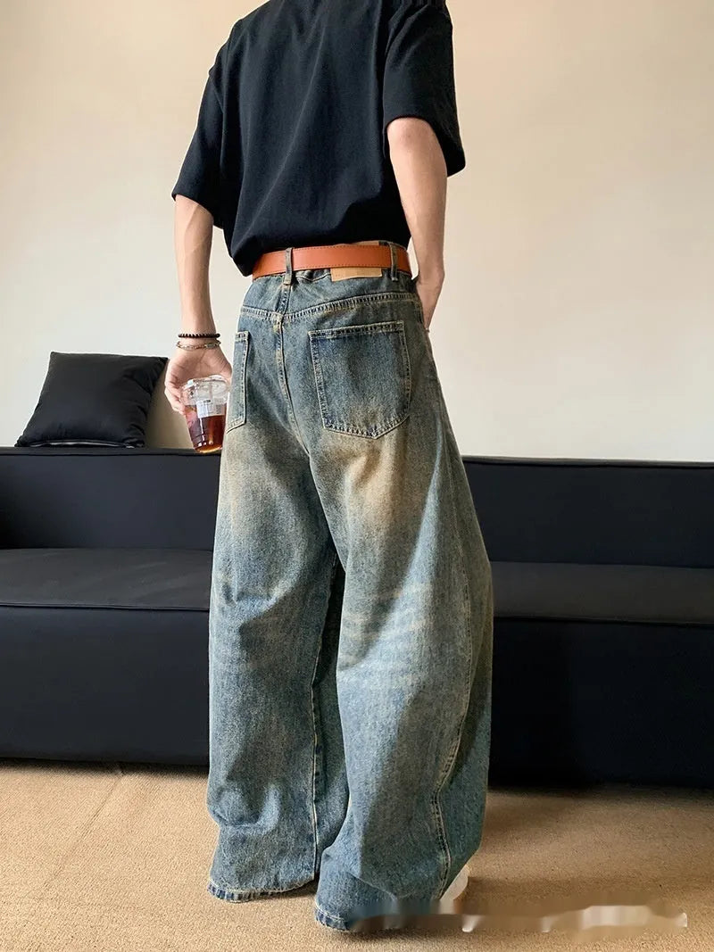 Man wearing retro blue distressed denim jeans with a slim-fit wide-leg cut.