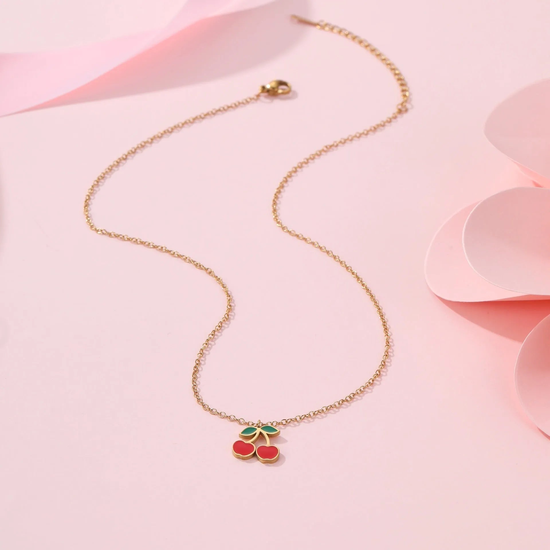 Cherry jewellery set showing necklace, bracelet, earrings and ring with geometric fruit designs on stainless steel chains