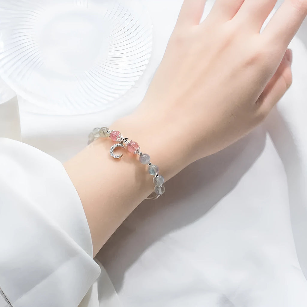 Simple handmade bracelet with round moonstone beads, a small crescent moon charm, and an adjustable metal clasp.