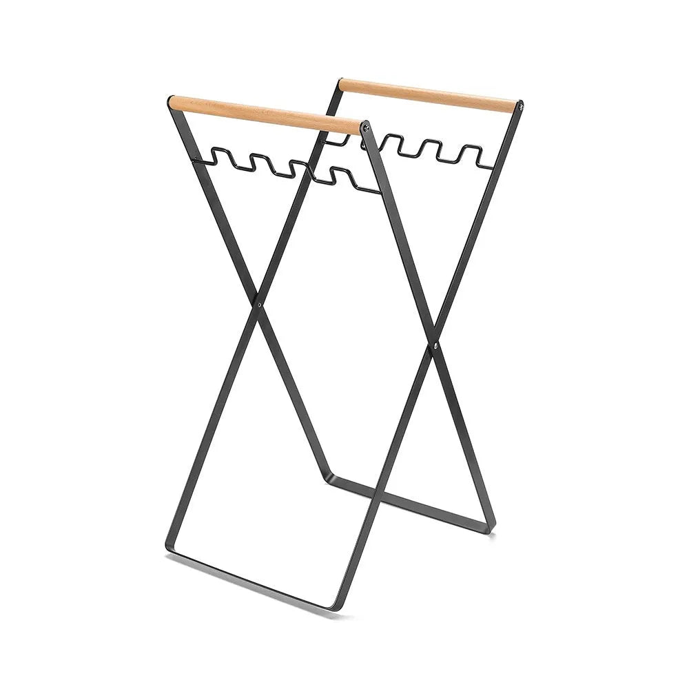 Black folding iron trash rack with wooden handles holding a bin bag outdoors