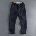 Men's khaki cotton work trousers with N buckle belt on a mid waist, showing three-dimensional cut.