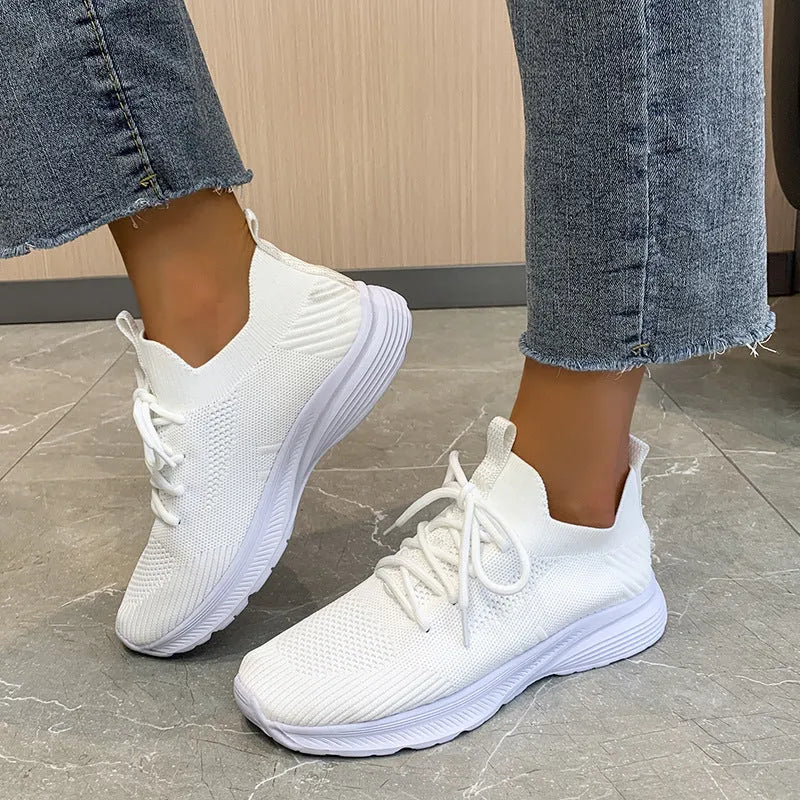 Women's low-top running shoes with mesh lining and Flyknit upper in creamy white, grey, or orange colours