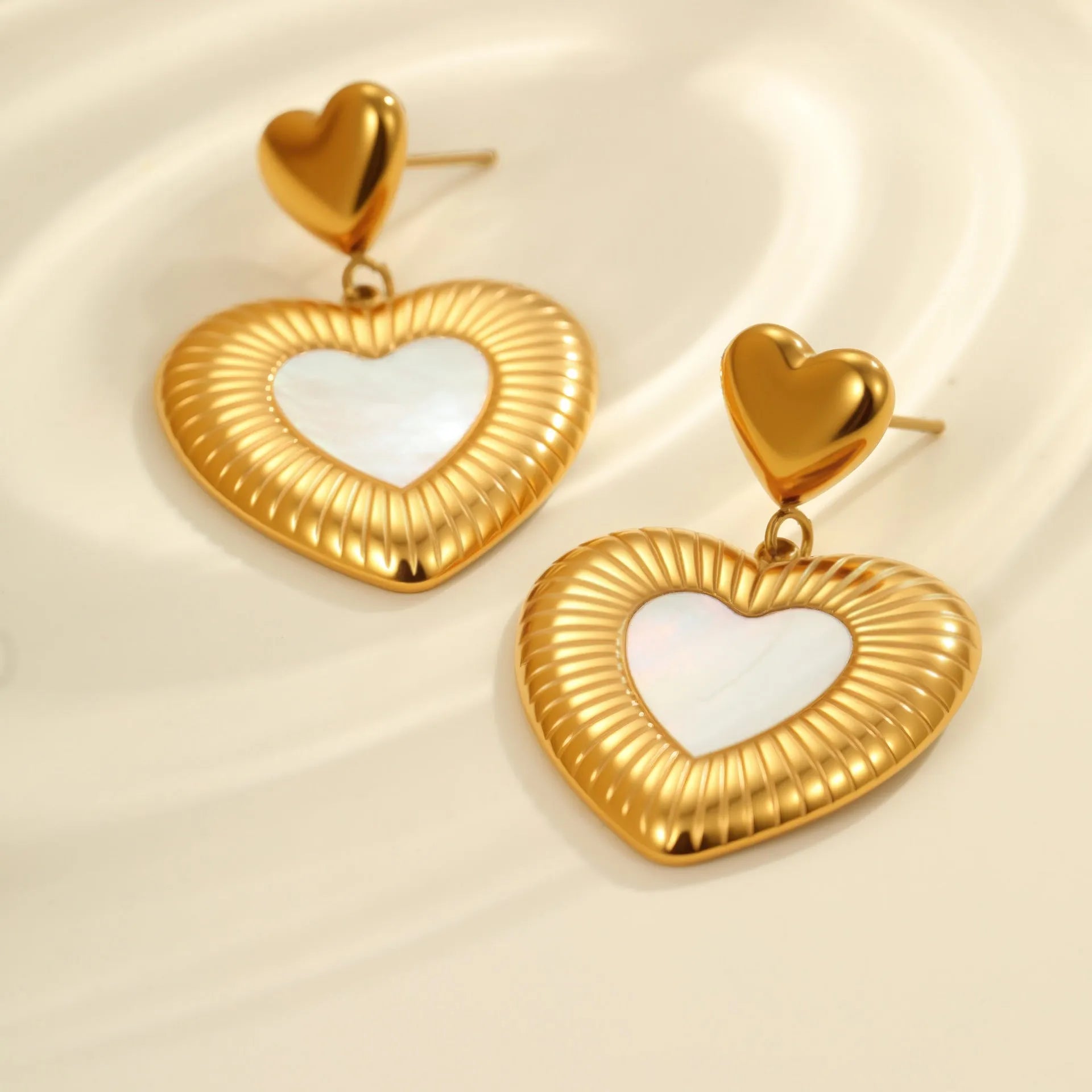 Gold heart-shaped stainless steel stud earrings for women with a love motif.