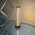 Glass cylindrical LED night light with magnetic base on a metal surface, showing USB charging port.