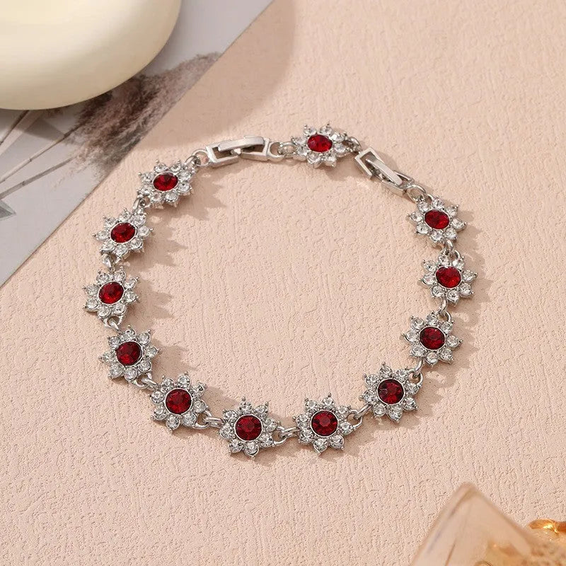 A gold or silver electroplated zinc alloy flower bracelet with coloured gems.