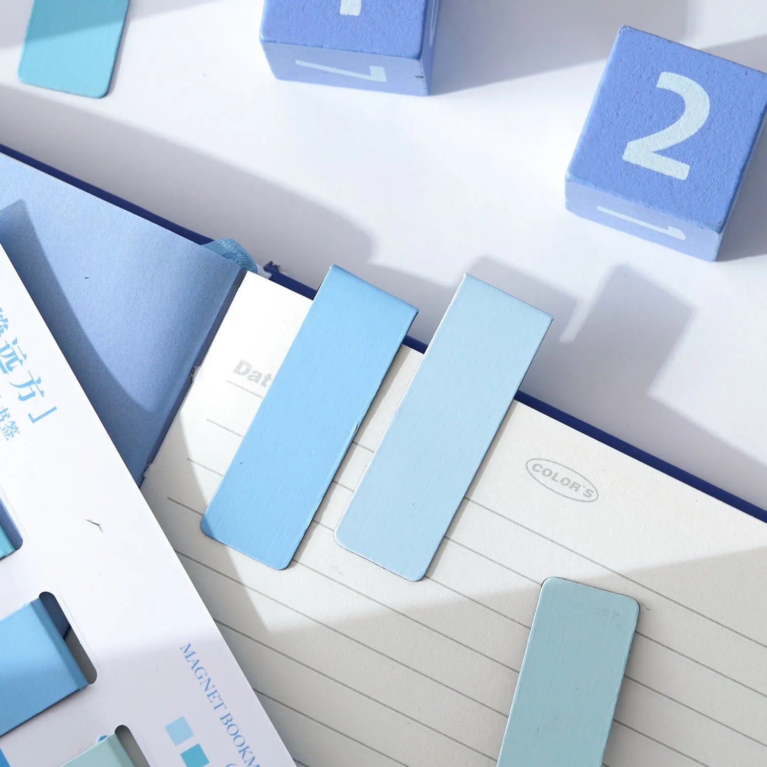 Set of four Morandi Series colour block magnetic bookmarks in pastel shades on a book page.