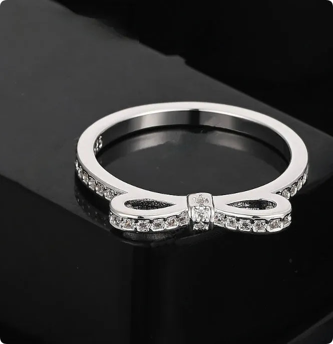 Silver bow-shaped rhinestone ring with zircon crystals on finger