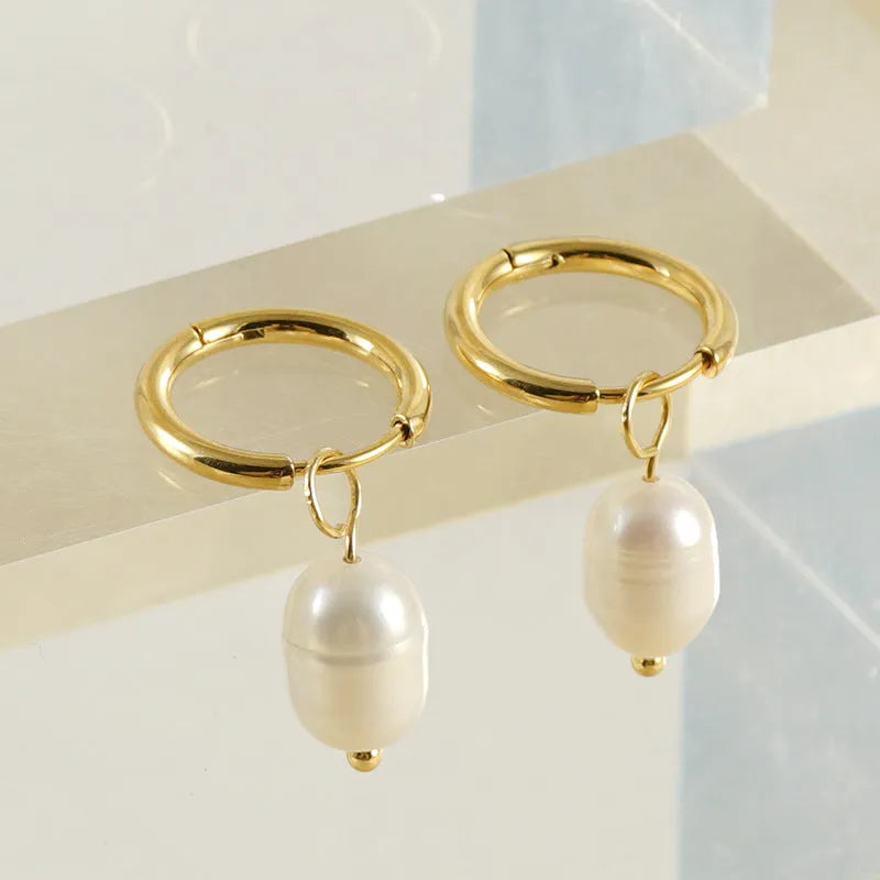 A pair of gold geometric earrings with a pearl detail on a stainless steel post.