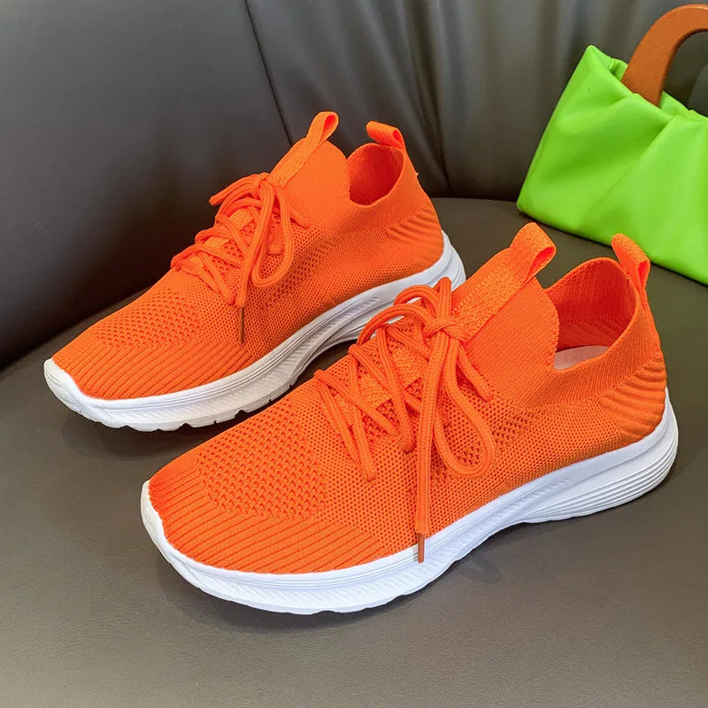 Women's low-top running shoes with mesh lining and Flyknit upper in creamy white, grey, or orange colours