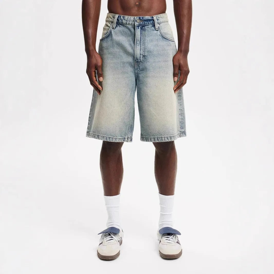 Man wearing loose straight leg jeans in light blue cotton denim, front and side view.